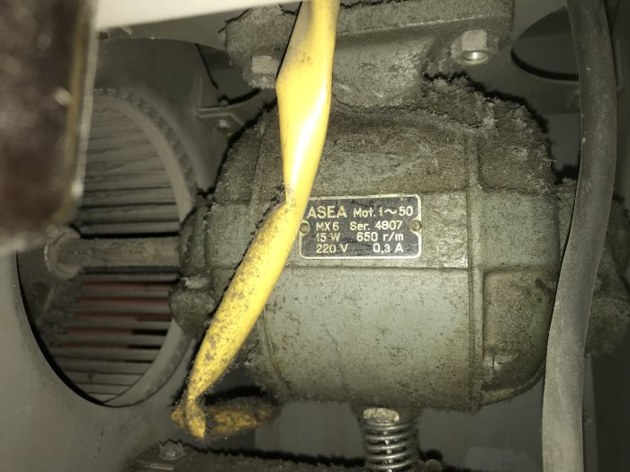 Dammig gammal ASEA motor från 1959 i ett ventilationssystem, med synlig beteckning och tekniska specifikationer.