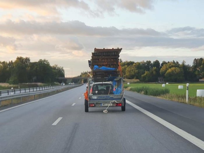 Överlastad släpvagn med osäkrade lastpallar på en väg.
