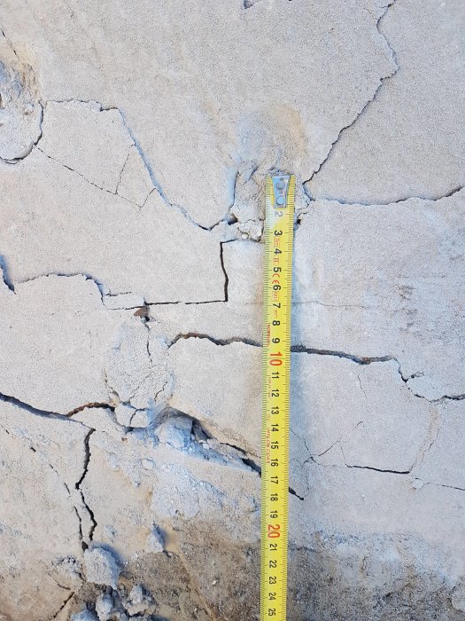 Måttband mot sprucken betongvägg för att mäta sprickans bredd.