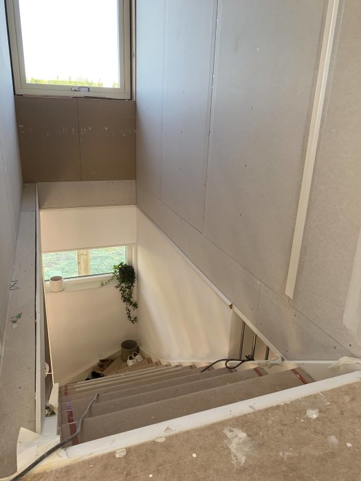 Övergången mellan gipsvägg på bottenplan och övervåning vid en trappa i en villa under renovering.