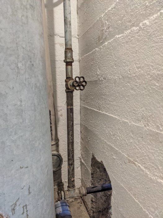 VVS-installation med stålrör, avstängningsventil och sidoanslutning ovanför plastledning.