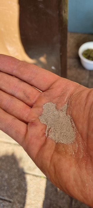 Sand i en öppen hand som illustrerar igensättning av munstycke i tråddiskussionen.