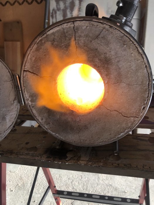 En glödande smidesässja med intensivt ljus i en verkstadsmiljö.