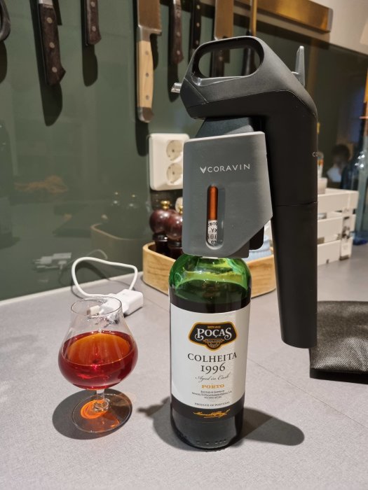 En halvflaska Poças Colheita 1996 portvin med ett glas bredvid och en Coravin vinöppnare.