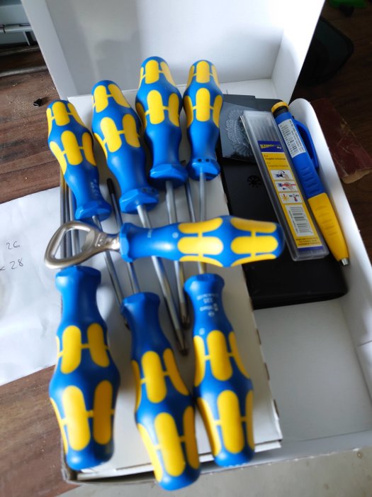 Set med blå och gula skruvmejslar och en cykelkedjerengörare i en vit kartong.