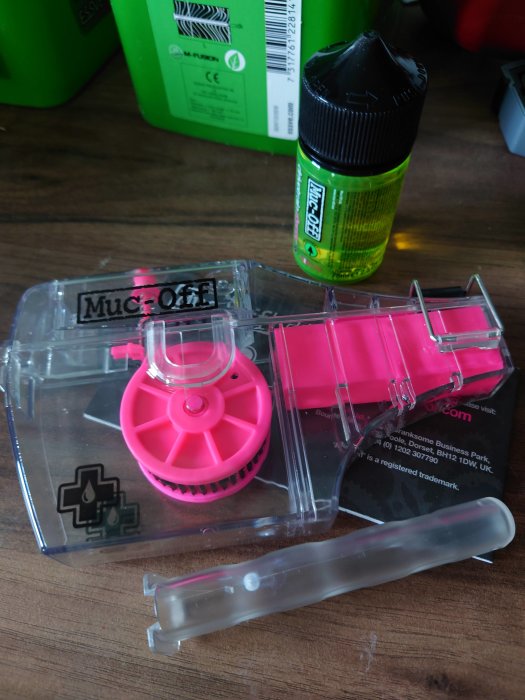 Rengöringsverktyg för cykelkedjor och en flaska med rengöringsmedel på ett bord.