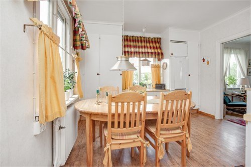 Ett befintligt ljust kök med ett runt träbord, stolar och lantliga detaljer.