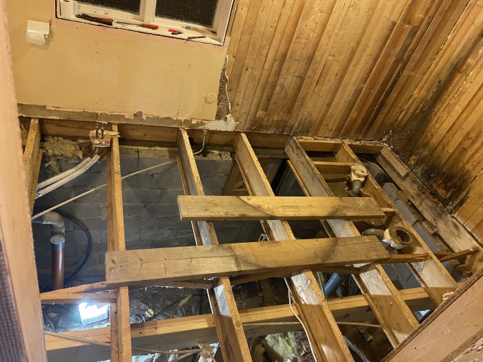 Rivningsarbete i badrum med synligt bjälklag och rörinstallationer inför installation av golvvärme.
