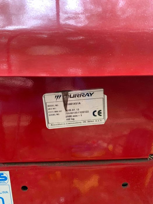 Röd gräsklippare av märket Murray, modellnummer och tekniska specifikationer visas på en etikett.