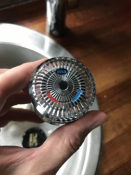Hand håller en kraninsats med varm- och kallmarkeringar.