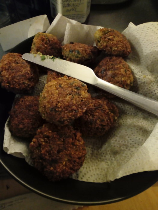 Hemlagad falafel på ett fat med tång för att servera, ojämnt staplade för att påminna om lutande tornet.