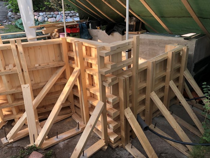Träkonstruktion för formarbete i byggprojekt under en presenning.