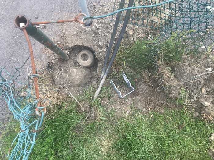 Staket med grävd mark visande en befintlig stolpe och två plintar bredvid ett hål i asfalten.
