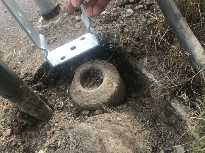 Grävd jord visar tre betongplintar nära en asfalterad yta, en med stolpe och stolpsko, och två andra isolerade.