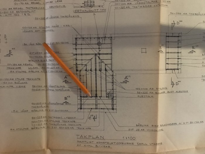 Ritning av takkonstruktion med måttangivelser, en penna pekar på en specifik del av ritningen.