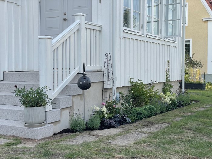 Husentré med nyplanterade rabatter och påbörjade konturer för grusgångar vid verandan.