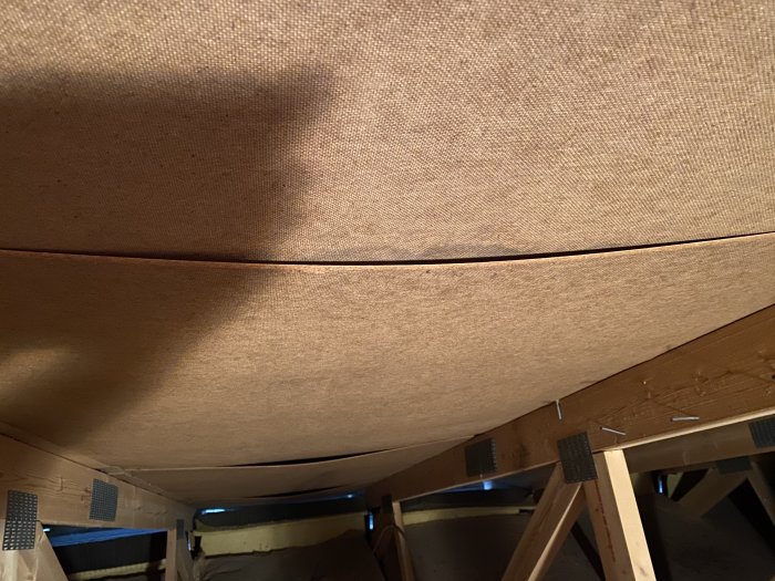 Lagad glipa mellan två träpaneler under en brun takbeklädnad i ett byggprojekt.