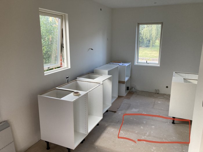 Ej färdigställt kök med golvspånskiva och markerat område där det knarrar.