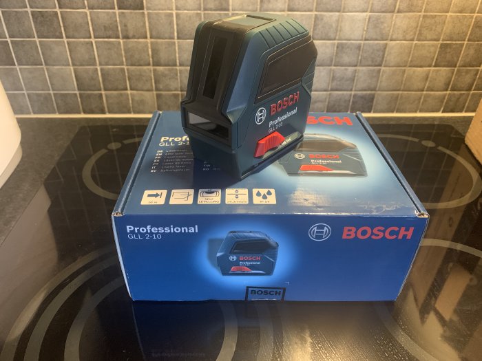 Blå Bosch krysslaser monterad på förpackningen på ett köksbord.