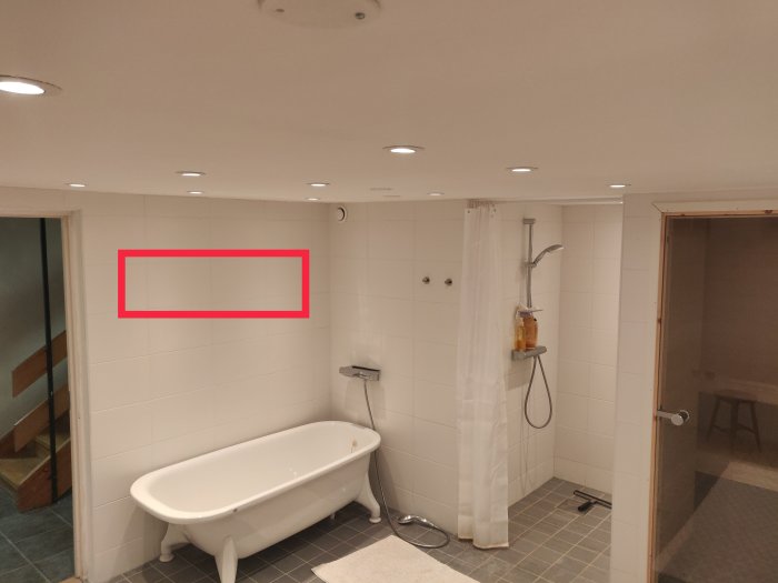 Ett tomt badrum med ett fristående badkar, dusch, och röd markeringsram där radiator planeras.