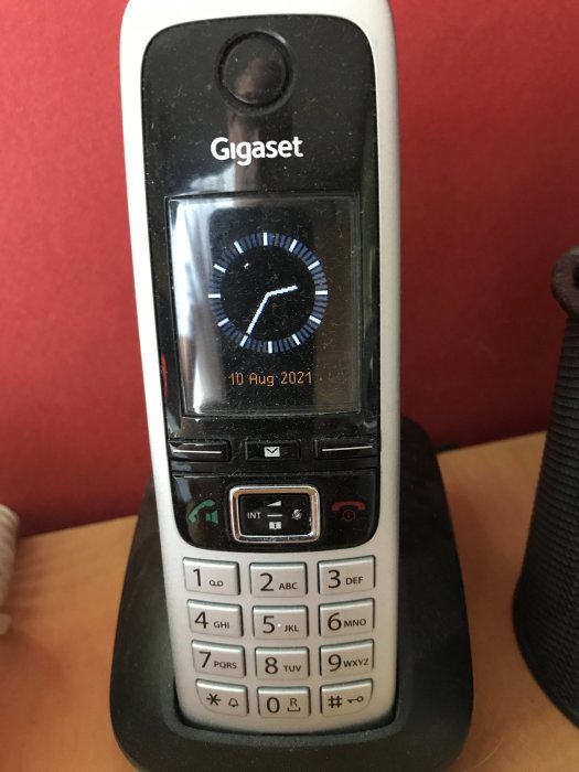 DECT-telefon Gigaset på laddningsstation visar datum 10 aug 2021 på skärmen.