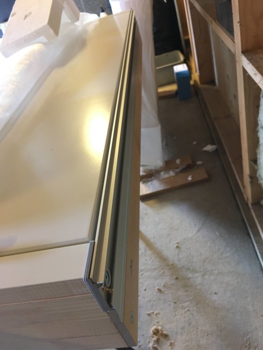 Sidovy av en ny, vit ytterdörr med en aluminiumtröskel och tröskelbleck som ska monteras.
