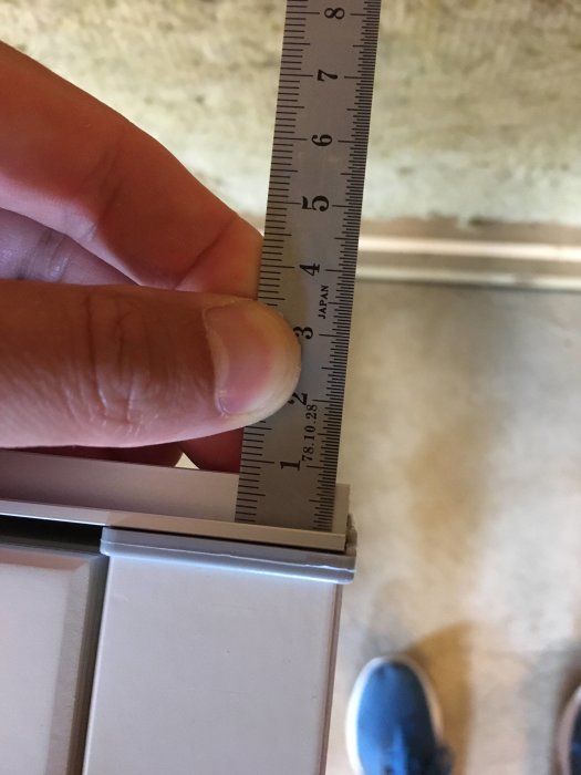 Mätning av en aluminiumtröskel till en ytterdörr med linjal som visar höjdmått.