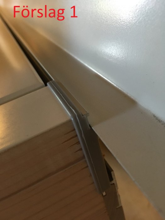 Tröskelbleck monterat på en tröskel i förslag ett, med tröskelblecket lutande inåt mot dörröppningen.