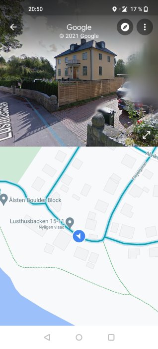 Gul villa med svart tak och balkong, inhägnad av staket, på Lusthusbacken med vägkarta.