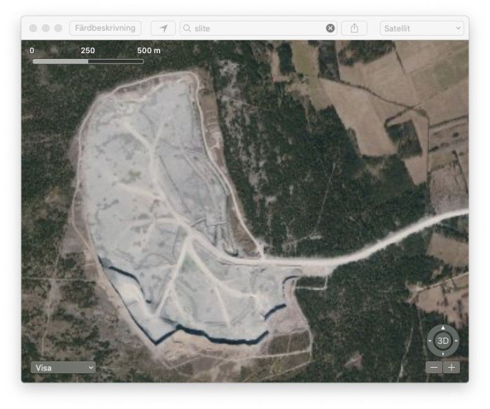 Satellitbild över en stor grustäkt omgiven av skogsområden.