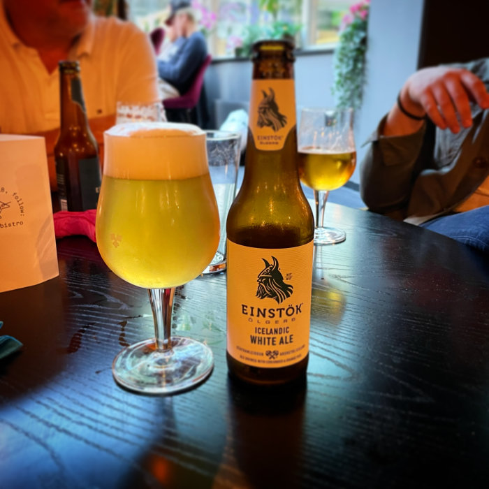 Flaska och glas med Einstök Icelandic White Ale på ett bord i ett bistromiljö.