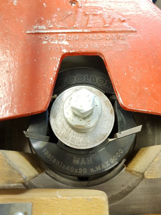 Närplan av en säkerhetskutter stämplad "MAN" från Toolbox monterad på en verkstadsutrustning med röda och trädetaljer.