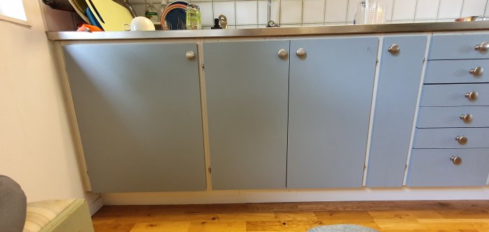 Köksinredning med grå skåpluckor där en diskmaskin ska installeras istället för det befintliga vänstra skåpet.
