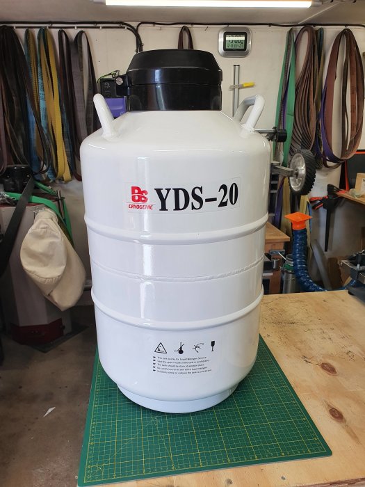 Kryogen lagringstank märkt YDS-20 i en verkstad, ombordstigningsverktyg och kablar i bakgrunden.