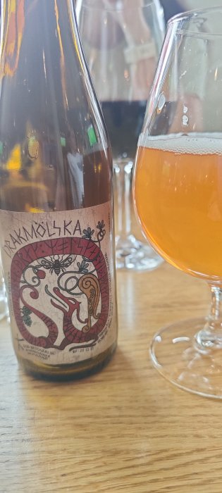 Flaska Drakmölka öl från Klövsjö på bord bredvid ett glas med öl.