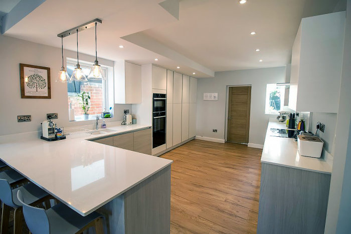 Modernt kök med sänkt tak som har inbyggda spotlights över vit köksö och köksbänkar.