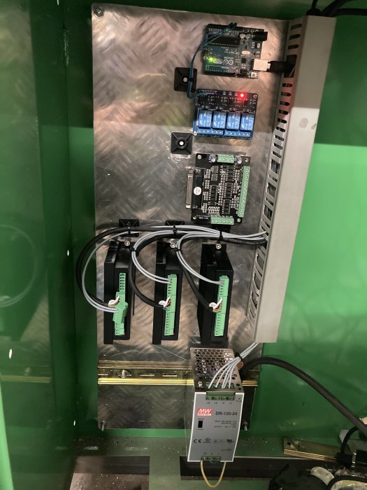 Elektronikkomponenter för CNC-plasma med kretskort och kablage på en metallplatta.