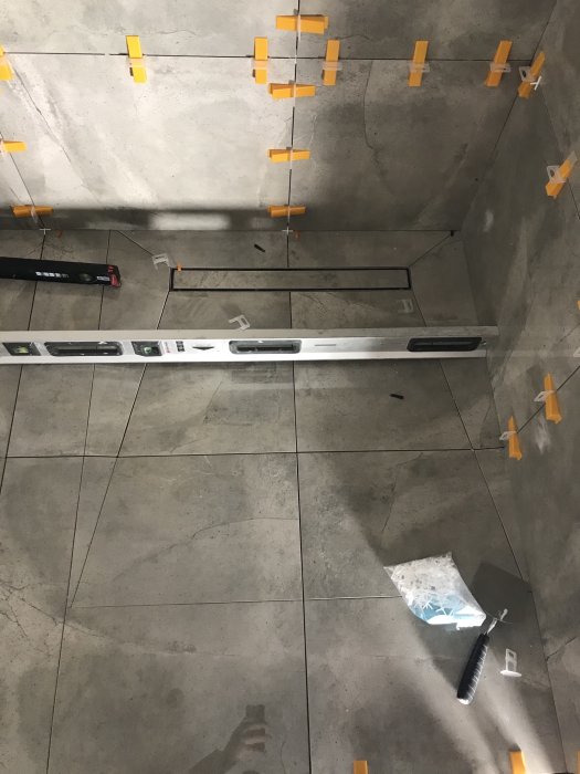 Installation av linjär brunnsavlopp i dusch med kakel och nivelleringskit.