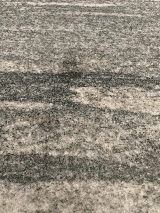 Fettfläck på granitbänkskiva i grått och vitt med mörkare fläckmönster.