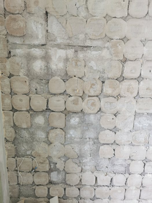 Væg med fjernede fliser og synligt fix, ujævnt fordelt, som viser misfarvning og fugtskader i et hjørne af huset.