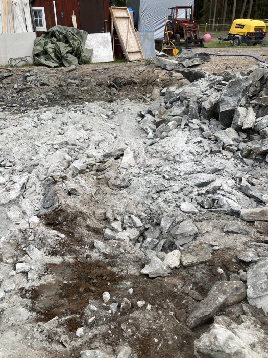 Borrat område med finfördelad sten och grus mellan större stenblock nära byggsajt.