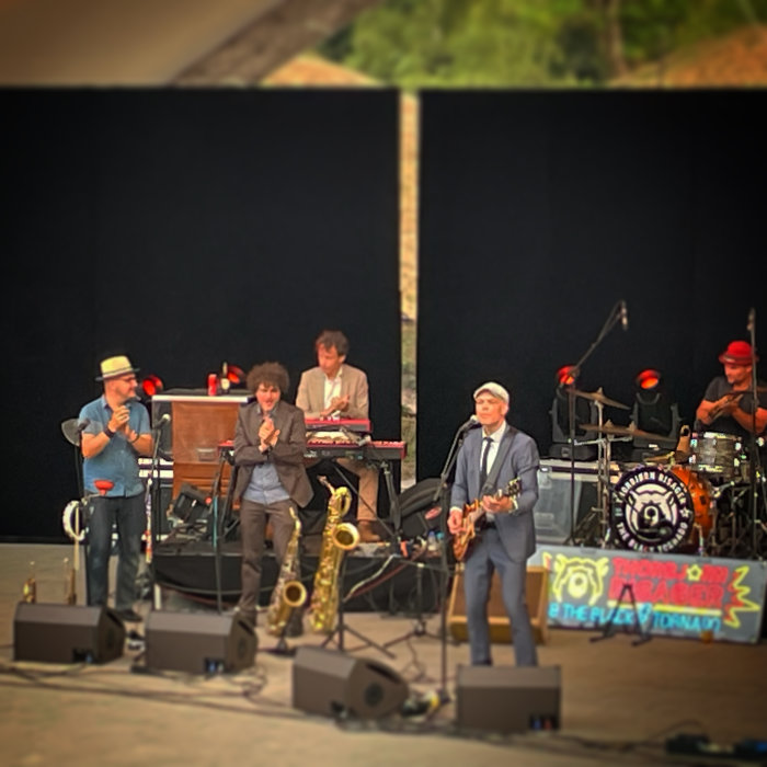Band uppträder på scen med instrument som gitarrer och saxofon.