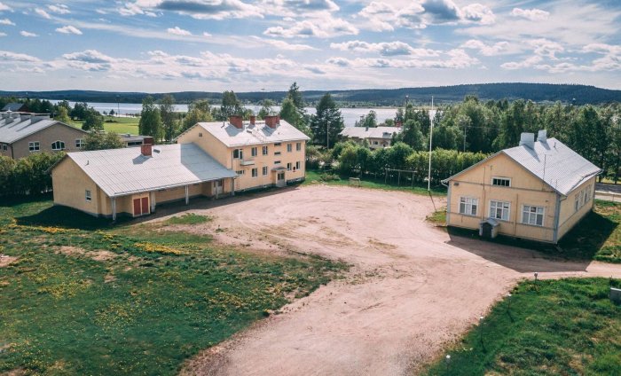 Flygvy över två stora gula hus med rött tak på öppen tomt, potentiellt för företagsverksamhet.