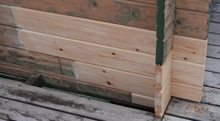 Renoverad husknut på en stuga med nya ljusa träbrädor som ersatt de svartmögelskadade delarna.