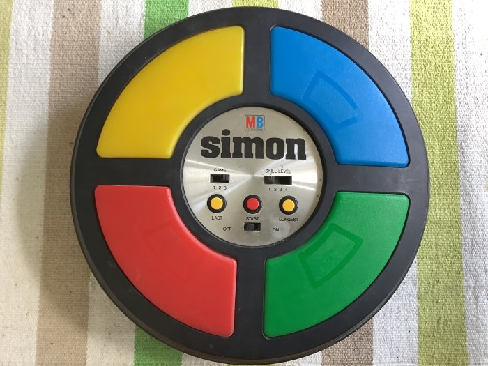 Retro Simon-spelet från 1980-talet med färgglada knappar på en textilbakgrund.