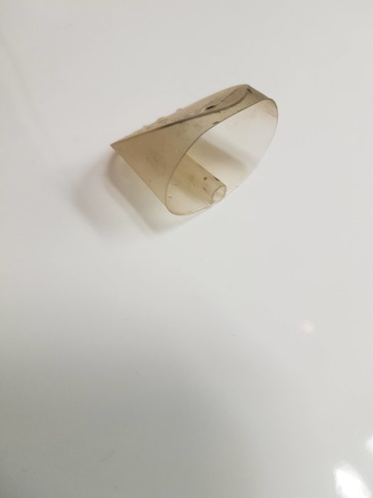 Smutsig silikonkil hittad i ett vattenlås, ligger på en vit yta.
