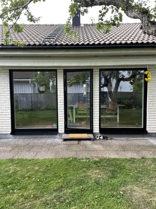Vitputsat hus med nya svarta aluminiumfönster ner till golv och synlig baksida.