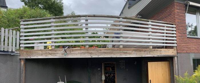 Tryckimpregnerade limträbalkar på altan oljade och delvis täckta av trall, en hammare synlig.