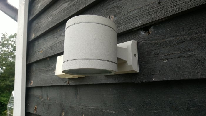 Fasadarmatur i grått monterad på svart trävägg, troligtvis modell Berylium eller liknande.
