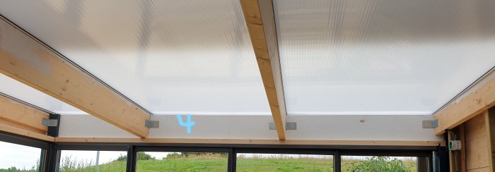 Delvis byggt uterum med isolerade golv och träbjälkar, indikation av ytan 4 med ett blått märke, i dagsljus.